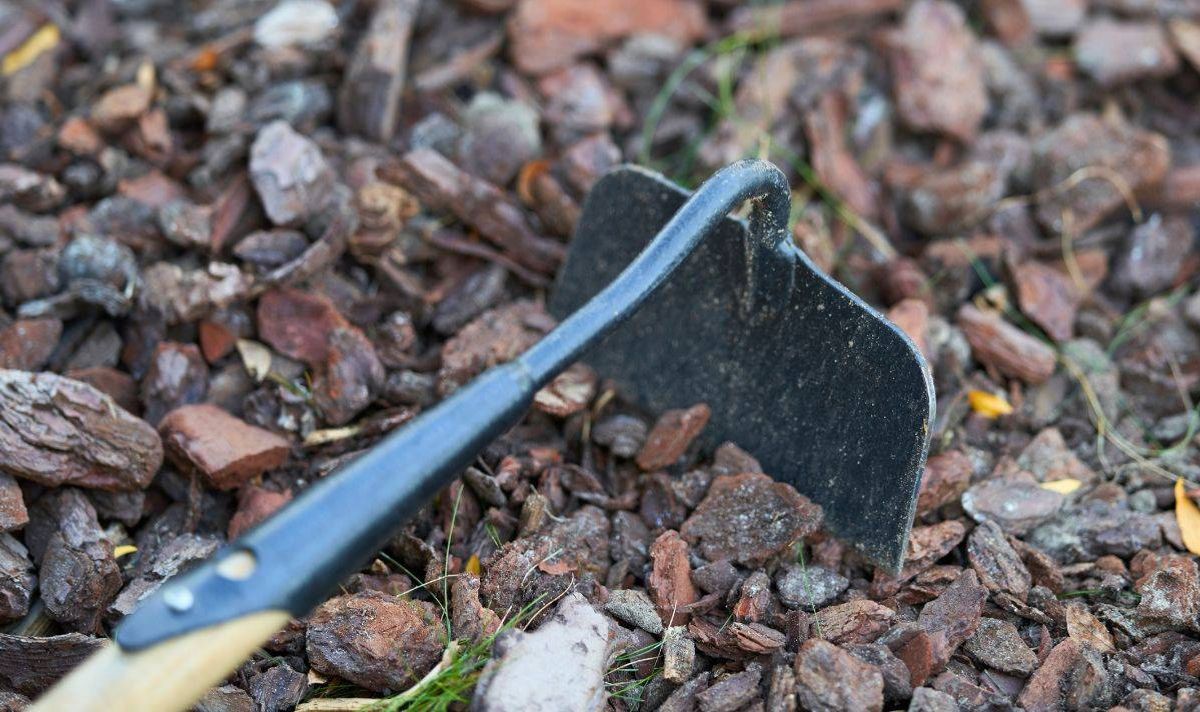Picture of someone using a hoe on gravel.