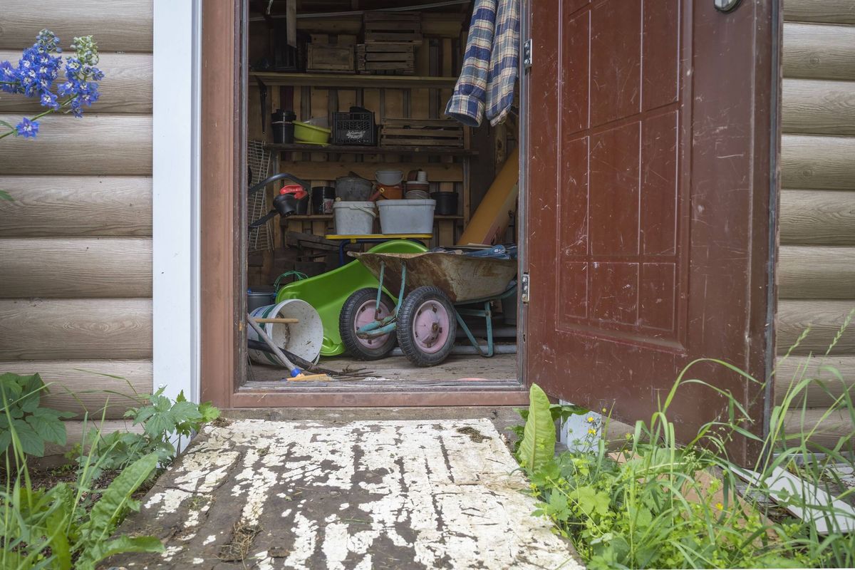 a shed with an open door in which there is a household garden equipment