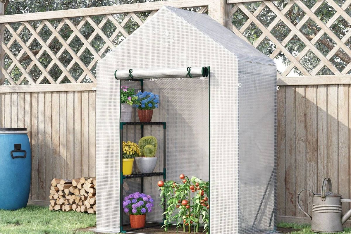 The Outsunny Greenhouse rolled up at the top in a garden