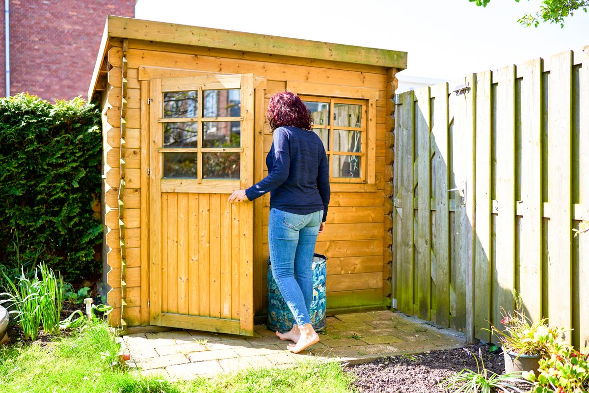Barefoot woman opening the door of a wooden shed