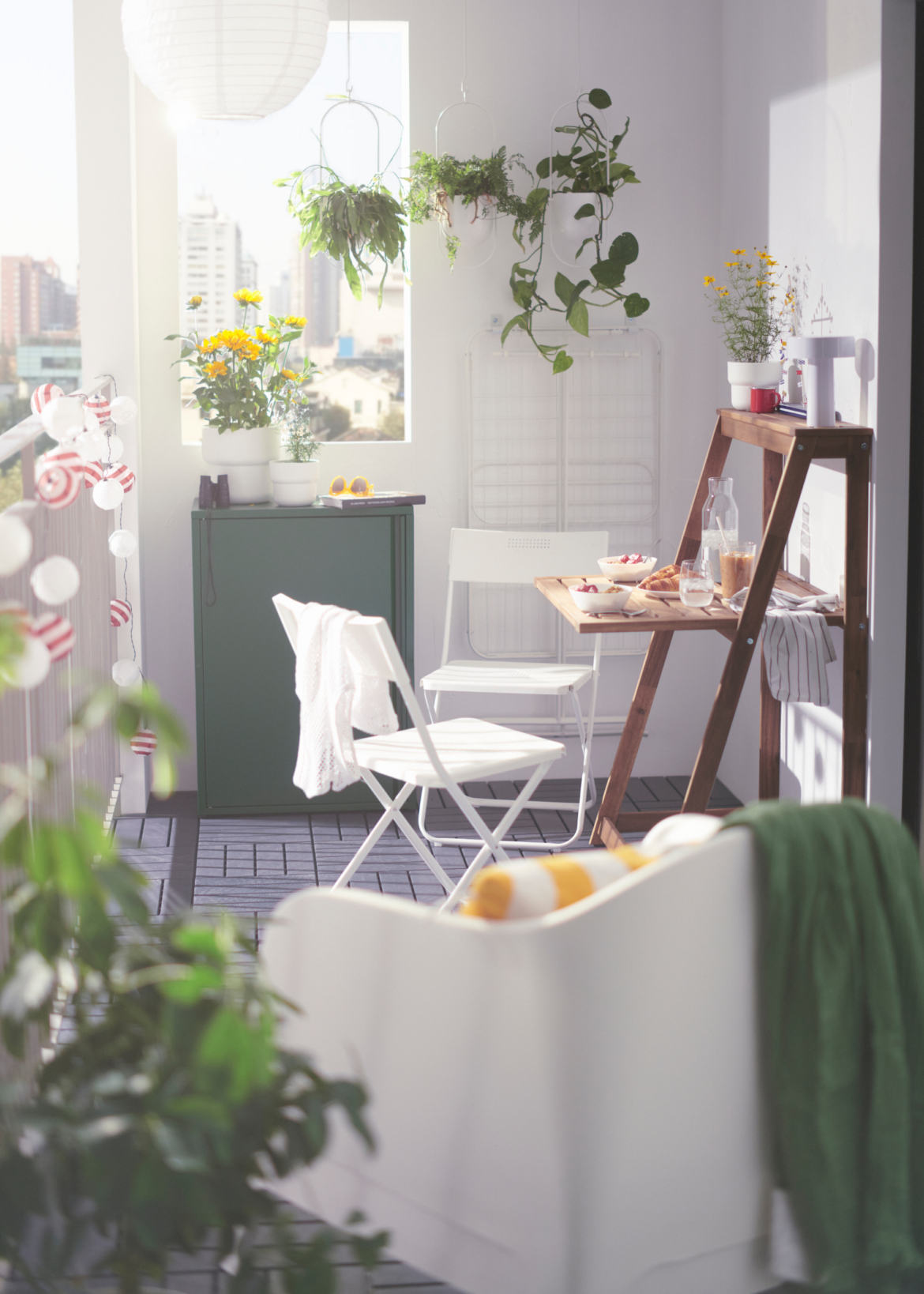 IKEA’s Folding Table Is the Ultimate Small Garden Flex | IKEA DJUPON Outdoor Folding Table unfolded on a balcony with two chairs surrounded by plants