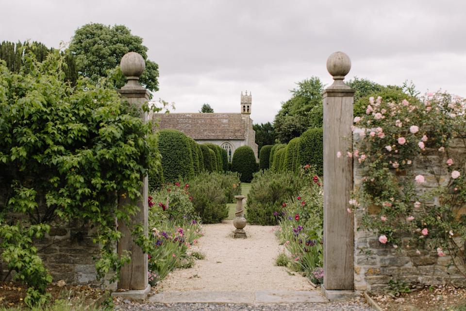 Pathway leading to a garden area with manicured hedges and floral arrangements.