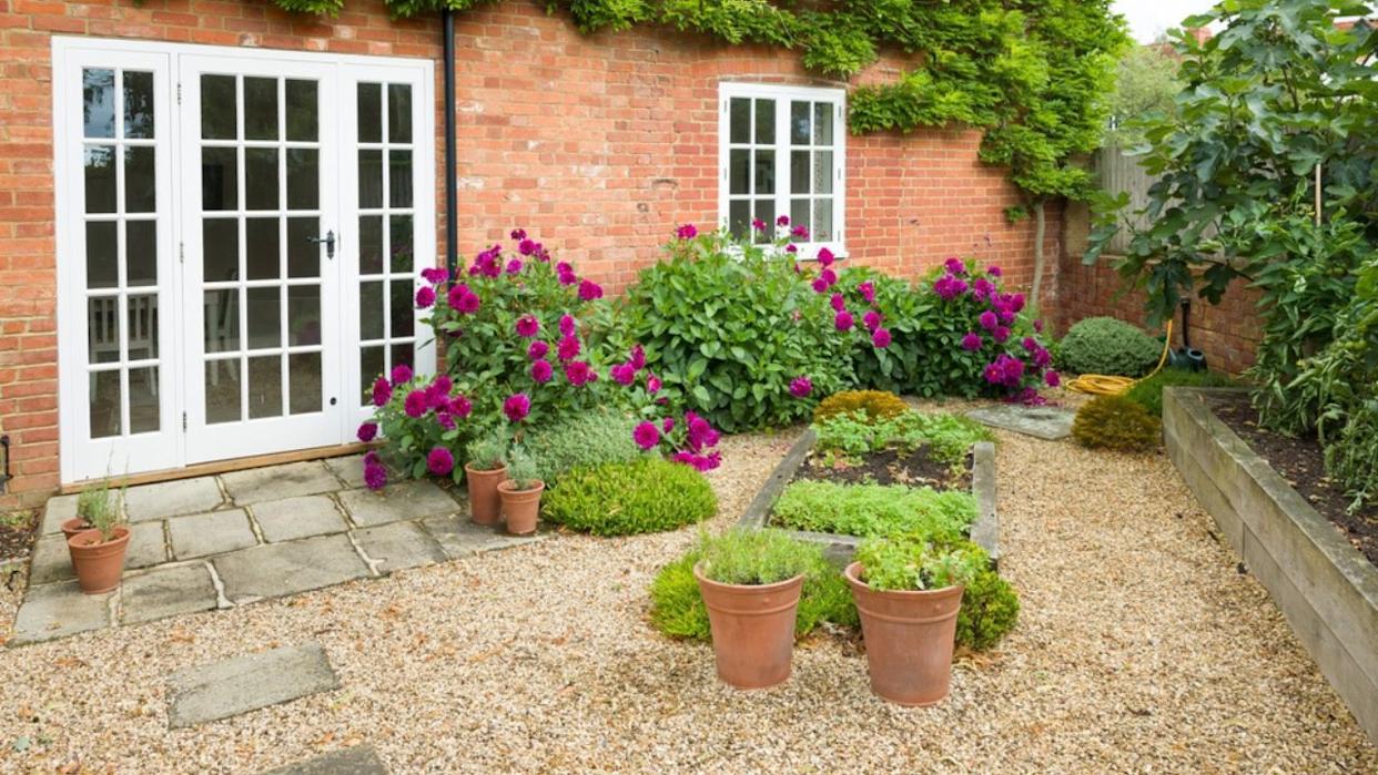 UK house and garden with patio and French doors. Cottage or courtyard garden (backyard) with gravel and York stone paving