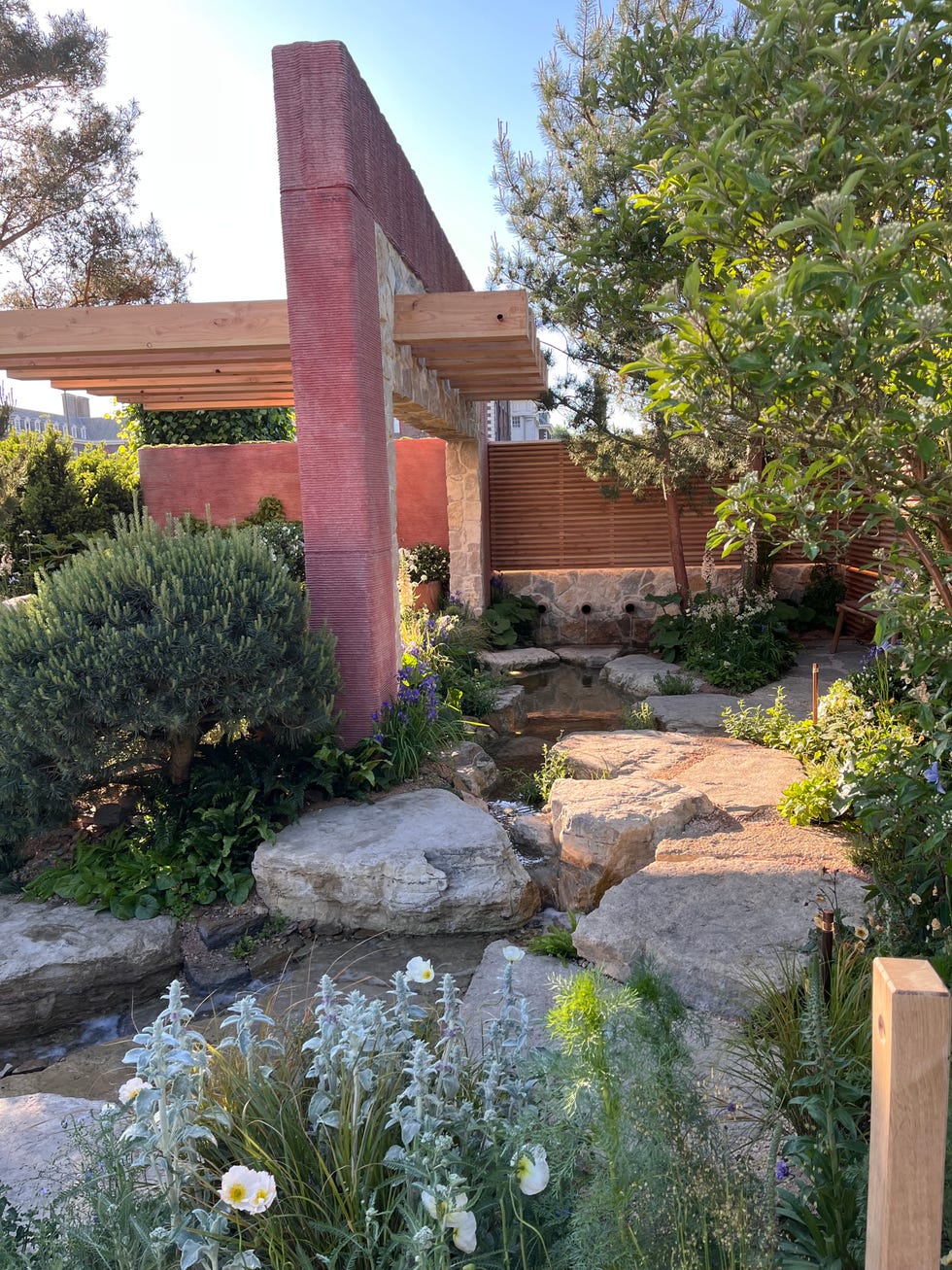 A garden landscape featuring stone elements, greenery, and wooden structures.