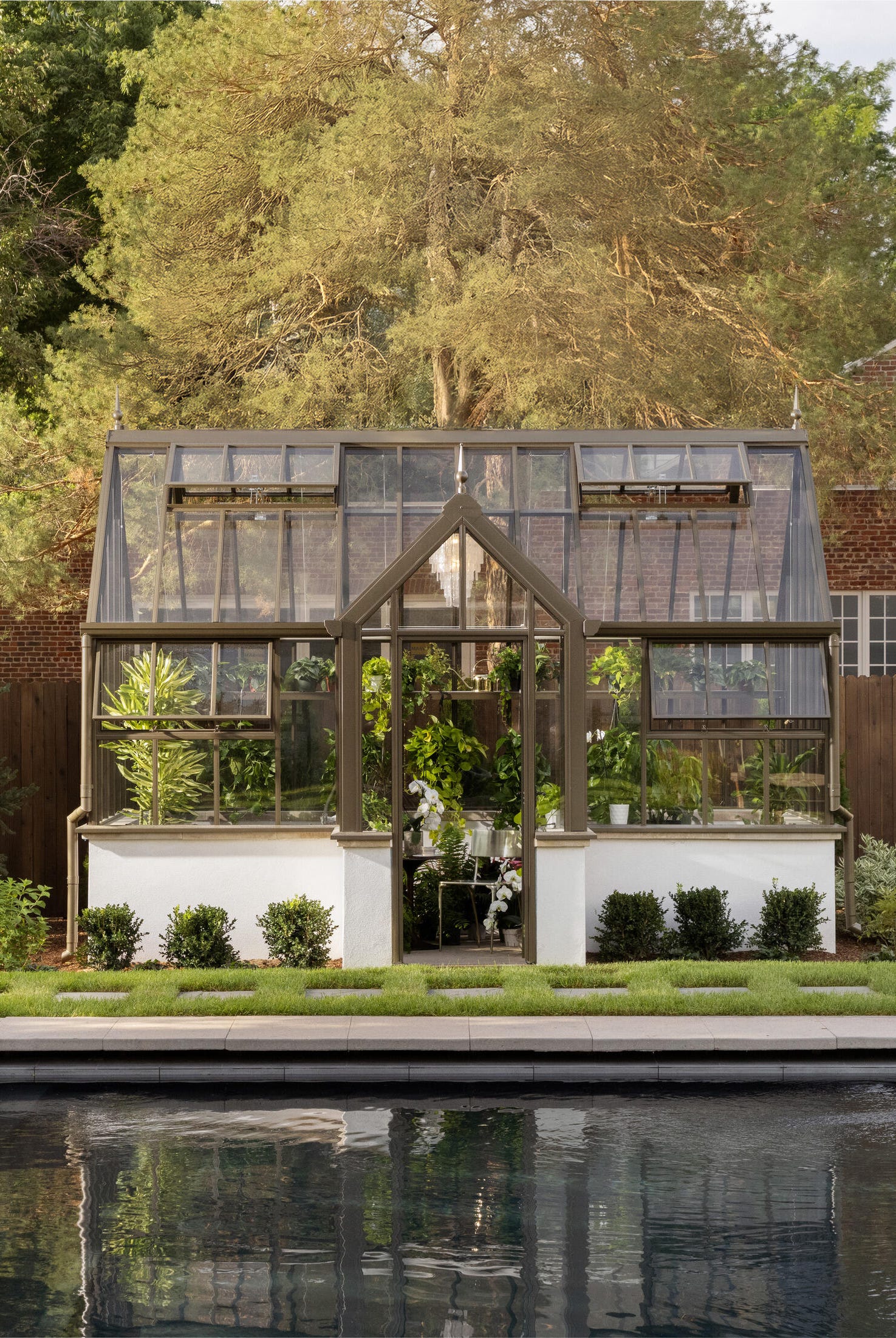 greenhouse surrounded by a lush garden and pool area