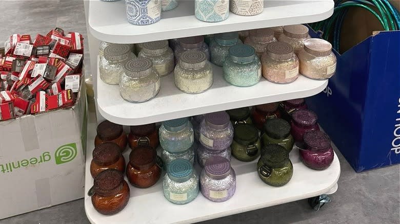 Colorful glass jar scented candles on shelves at Dollar Tree.