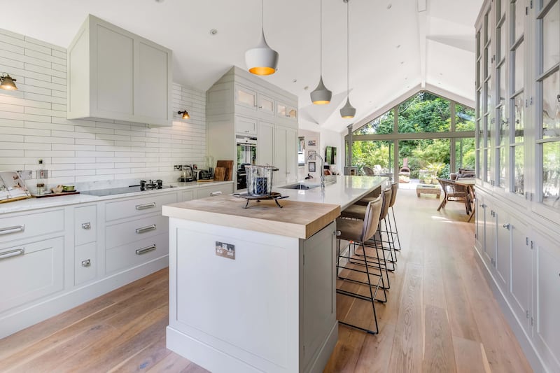 The all-white kitchen is centred by a marble topped island