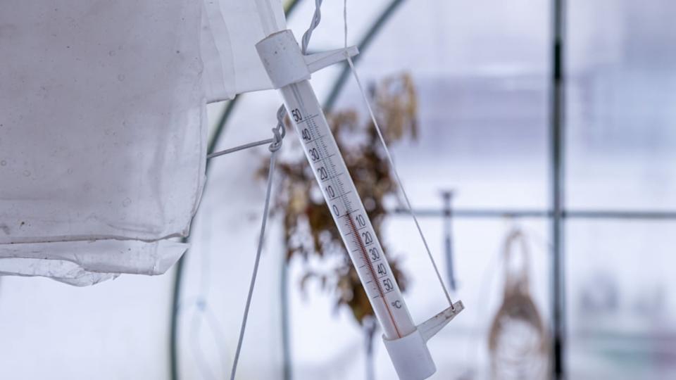Mercury thermometer in a greenhouse, outside the house shows cold weather below zero