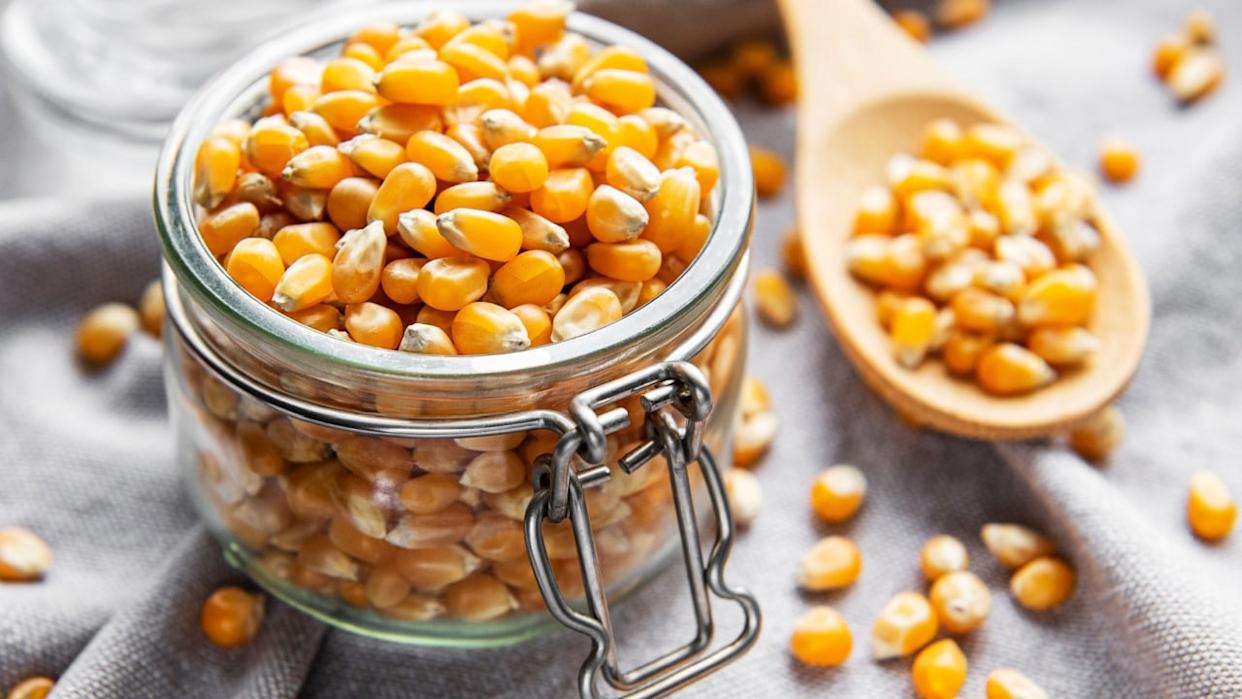 Dry Corn seeds in jar and bowl on grey textile background