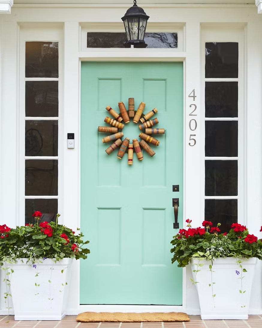 Front door with a decorative wreath and potted plants. Front door with a decorative wreath and potted plants.