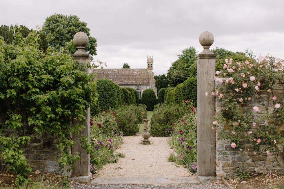 Pathway leading to a garden area with manicured hedges and floral arrangements.