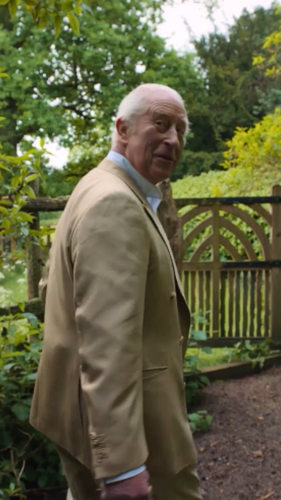 King Charles in a suit collecting chicken eggs.