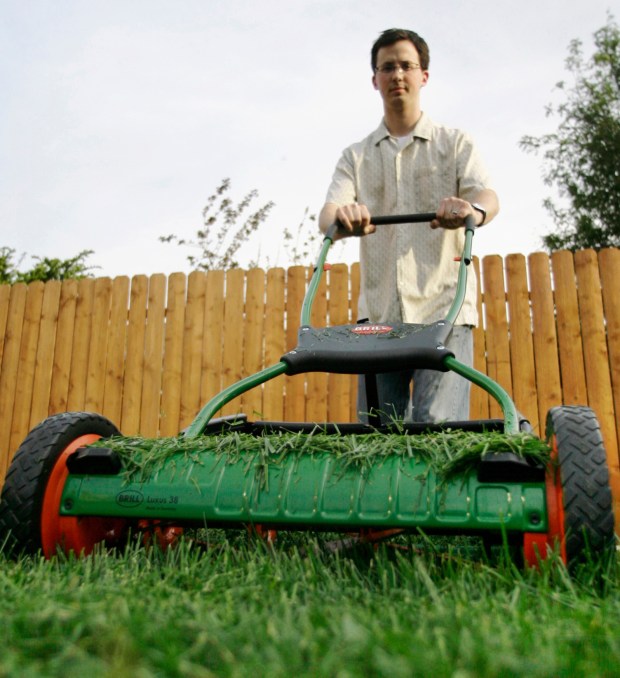 A man uses a manual lawn mower to cut his lawn in Chicago.