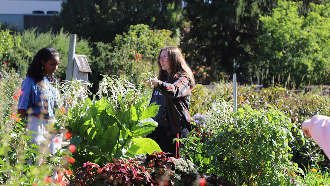 Christine Barta (right) points out plants on a high school tour of gardens on East Campus.