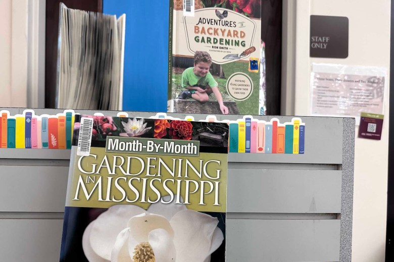 A closeup of a shelf with the books 'Month-by-Month Gardening in Mississippi' and 'Adventures II Backyard Gardening'