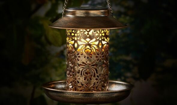 Solar Light Bird Feeder in gold illuminating at night.