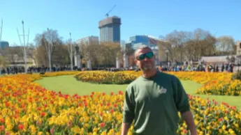 Smiling Karl Stevens, in front of a sea of yellow and red flowers