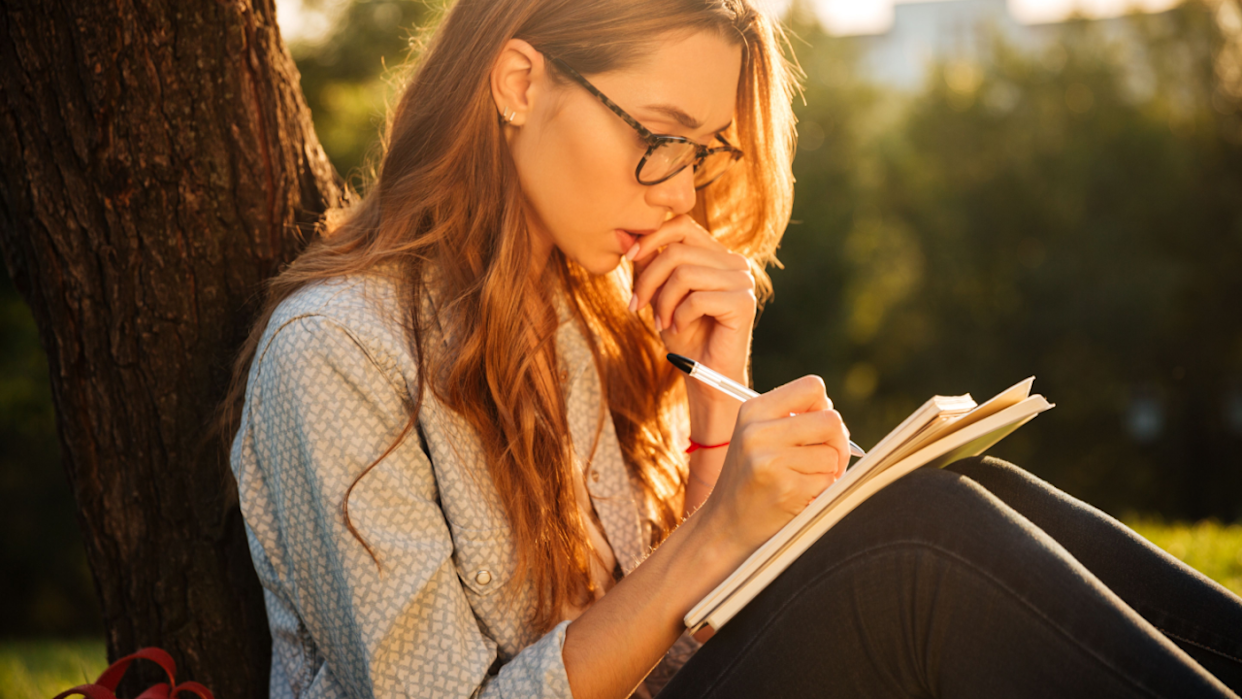 woman journaling outside thinking glasses pensive