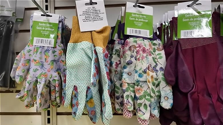 Dollar Tree garden gloves hanging on hooks in a store.