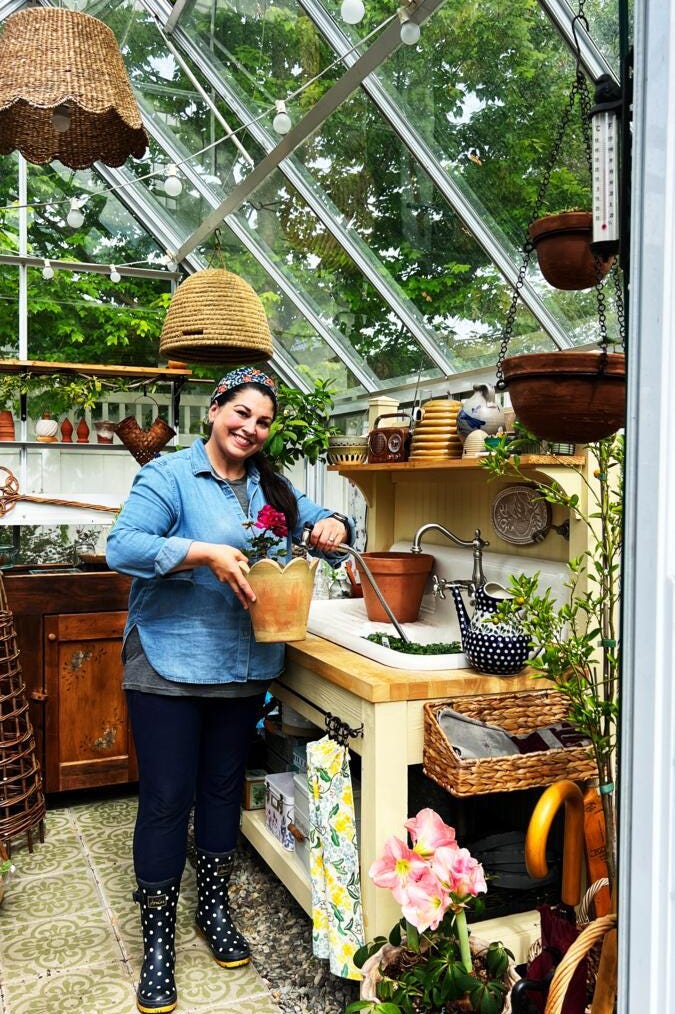 a person watering plants in a greenhouse
