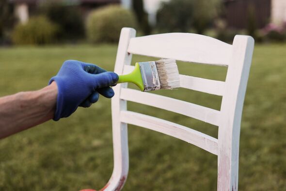 Painting wooden chair with a brush in white paint. Renovation garden furniture.