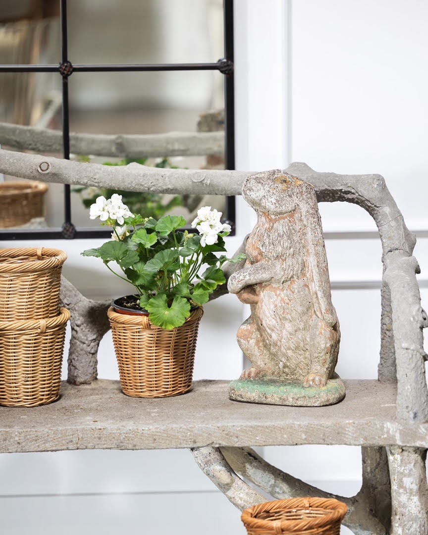 Decorative faux bois bench with potted plant and a rabbit statue on a shelf.