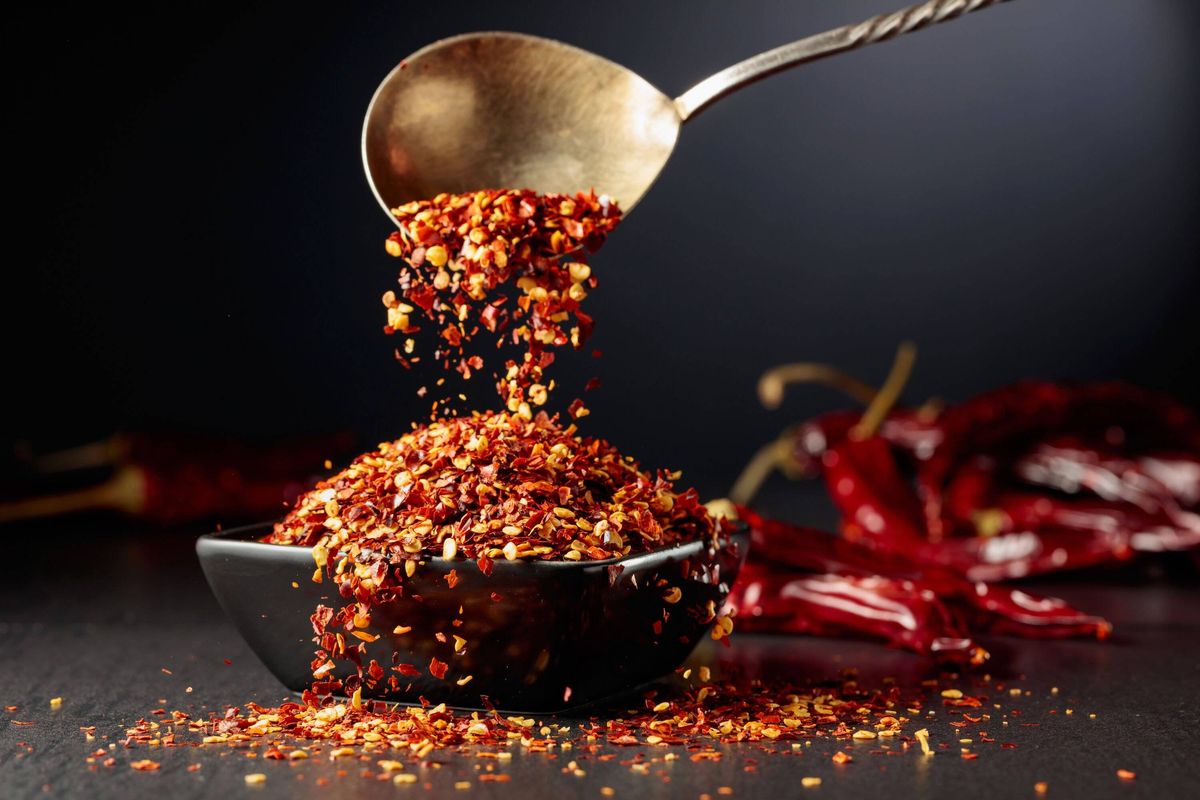 Chilli flakes are poured into a black dish.