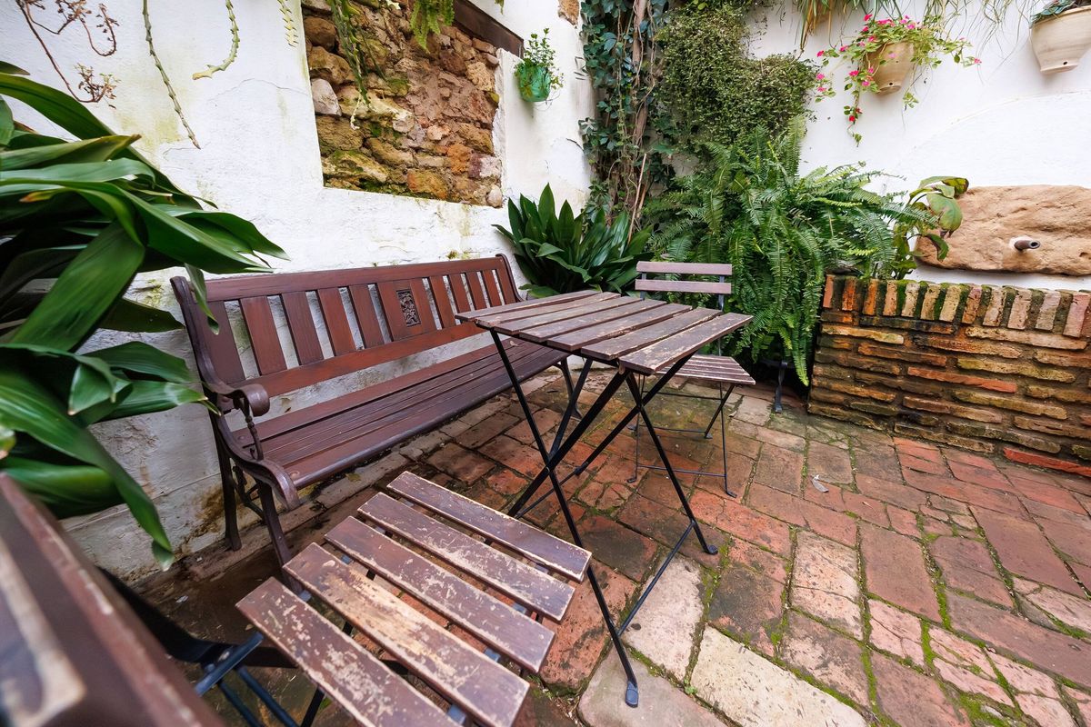 Courtyard corner in Cordoba with table, chairs, bench, and tiles
