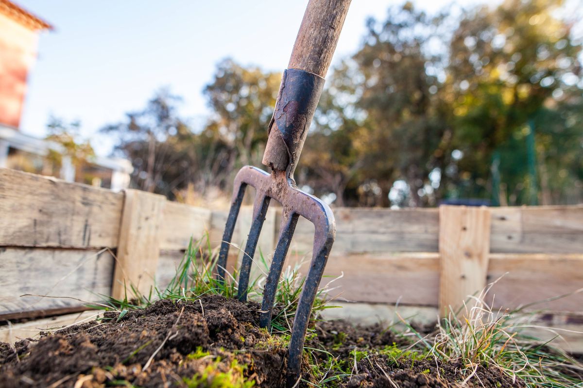 Cette photographie présente une fourche planté dans de la terre, en préparation du jardin pour le printemps.