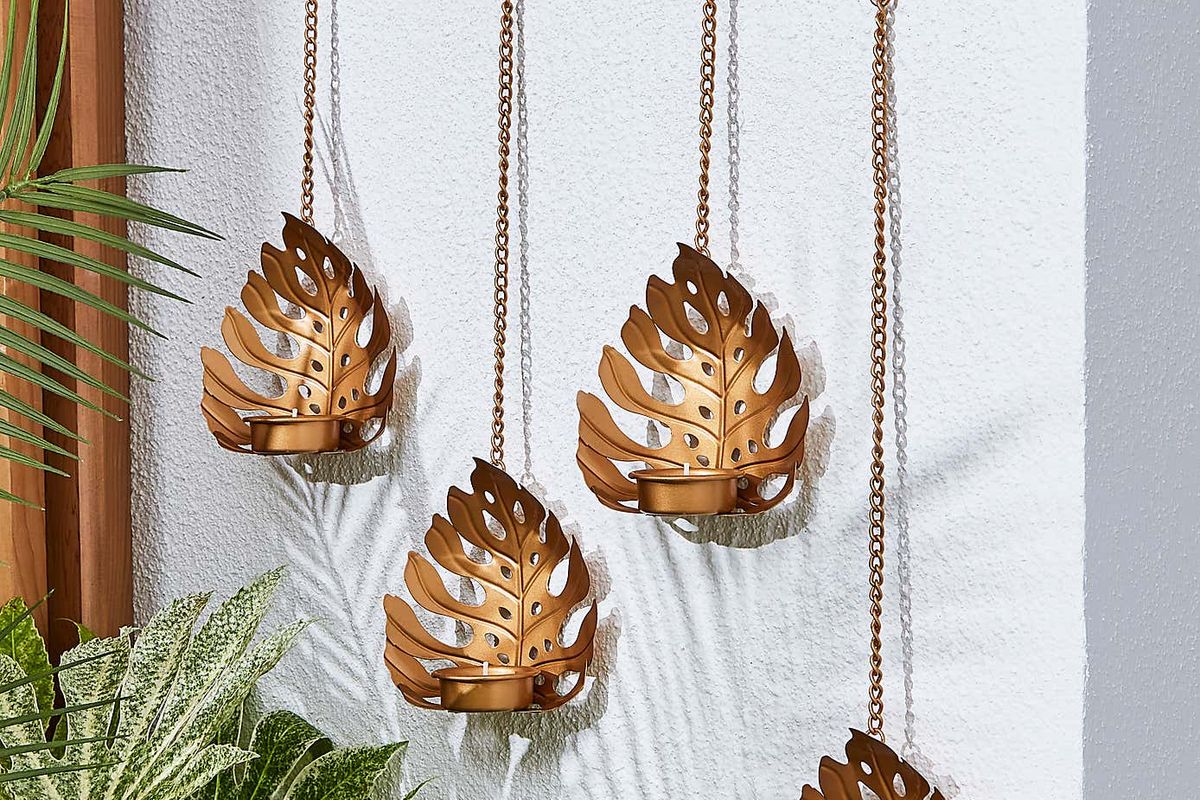 An image of leaf-shaped hanging tealights on a garden wall