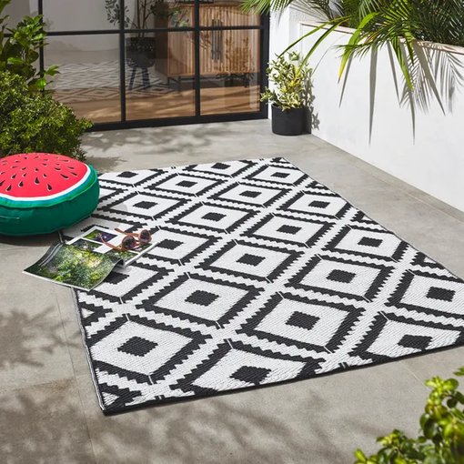 An image of a geometric patterned rug and furniture in a garden space