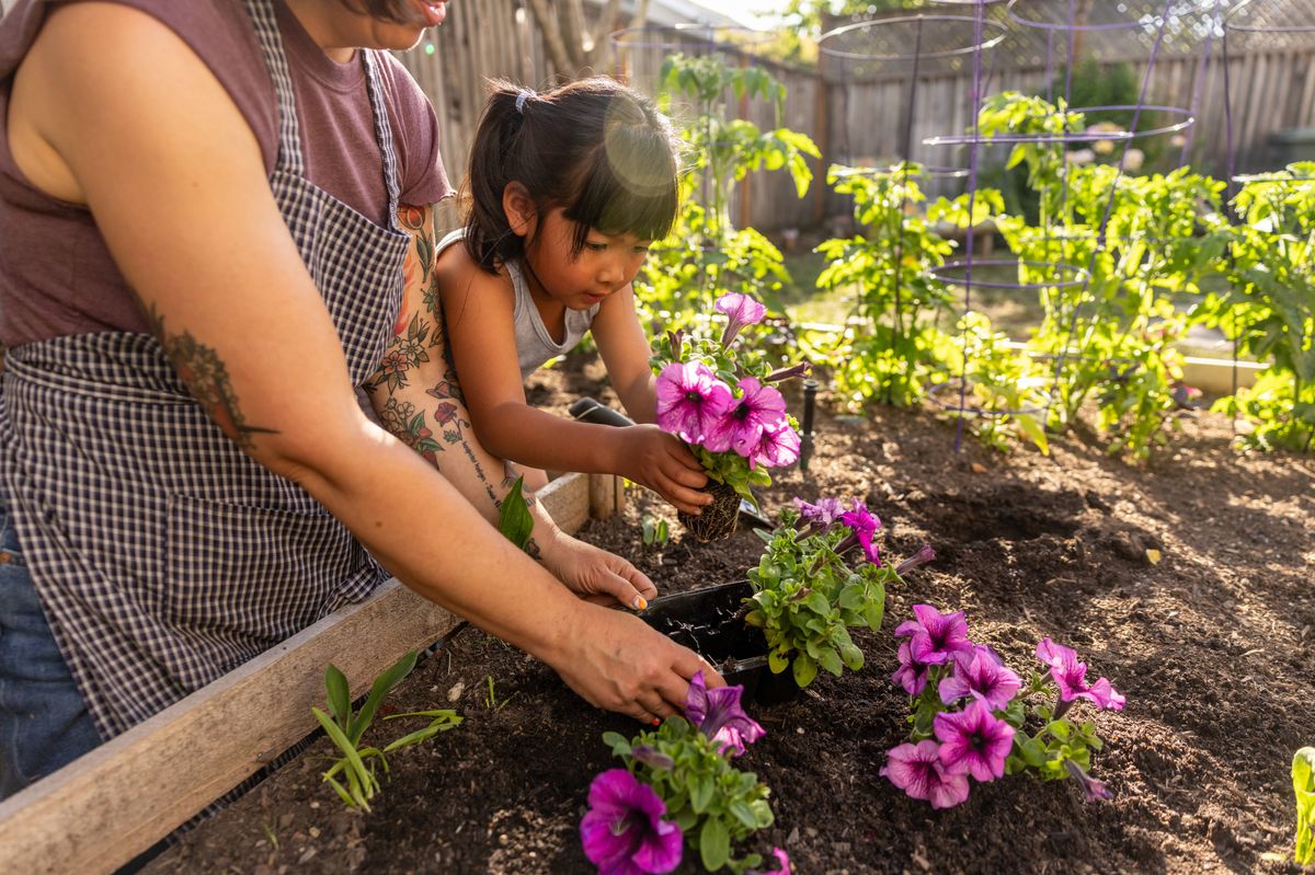 Woman teaching a child how to garden. Tending flowers, herbs and vegetables.