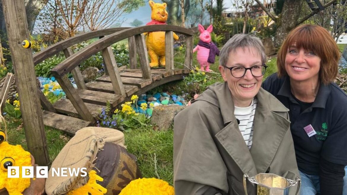 ‘Harrogate show garden celebrates differences – like our charity’ Two women sit in a highly-designed garden next to prop honey pots with a bridge in the background and model Winnie the Poo and Piglet characters.