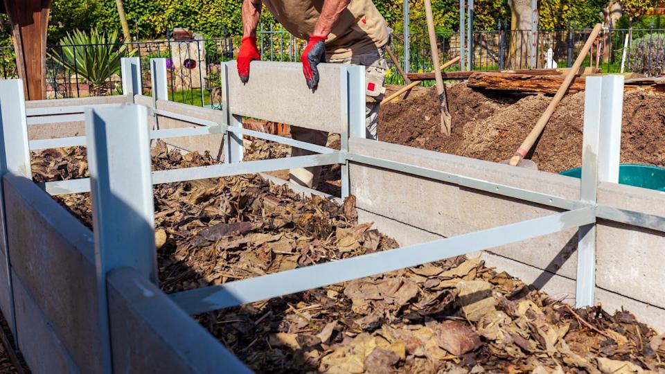 Construction of a raised bed with Edging Stones and double T steel profile filling with rough mulch and ground in Residential garden, private vegetable garden. Landscape design in home garden.