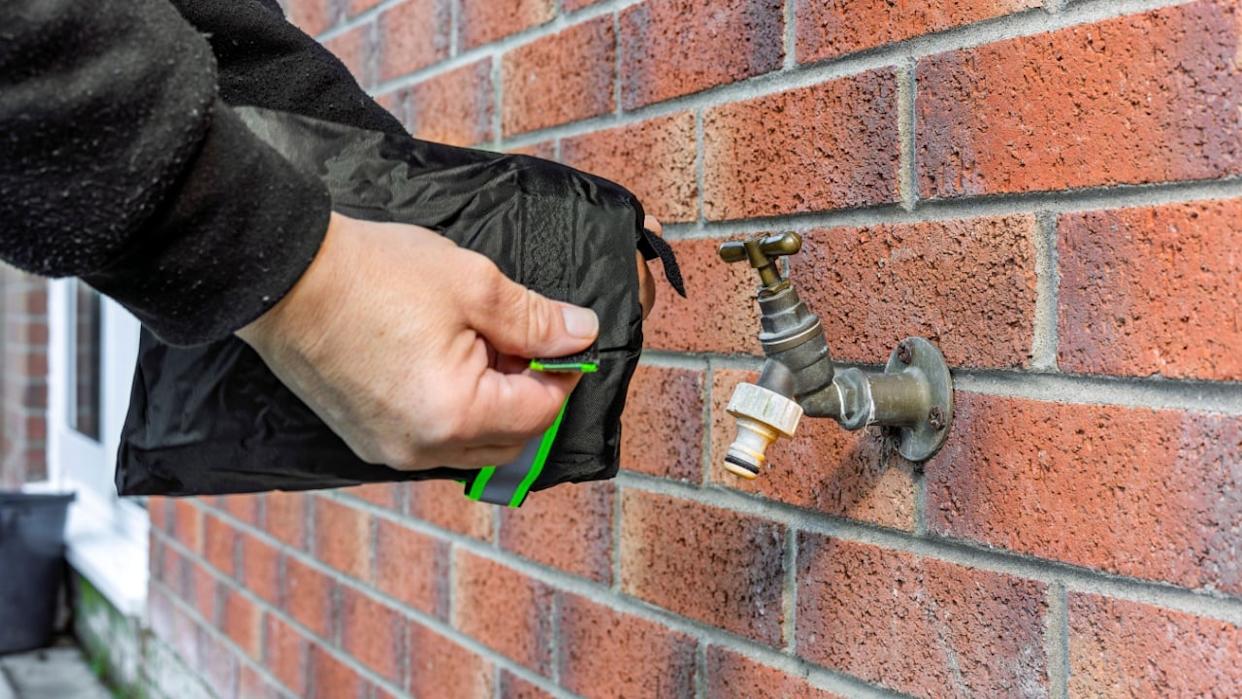 Person Installing Winter Frost Protection Insulated Tap Cover on Brass Garden Brick Wall Water Faucet