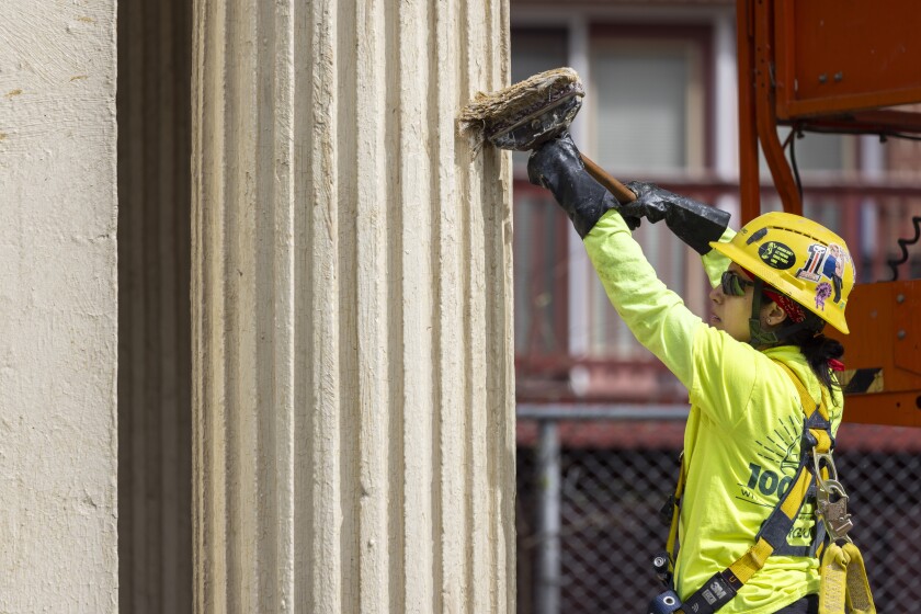 A construction worker rubs a brush against one of the pergola's fluted columns.