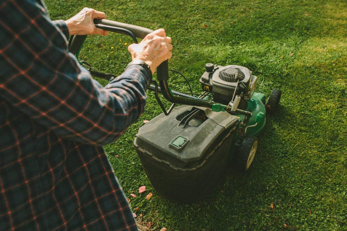 Senior Woman Mowing the Lawn in a Rustic Garden Setting