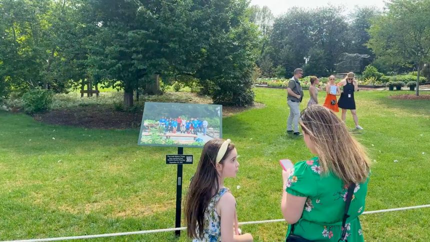 Visitors look at a sign in near the White House Kitchen Garden, featuring First Lady Melania Trump participating in a harvesting and planting event with the Boys and Girls Club of Greater Washington September, 2017 during the White House 2026 Spring Garden Tour on Saturday.