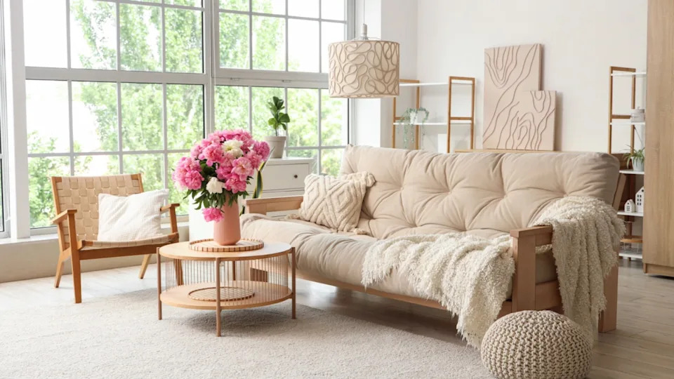 Armchair, sofa and coffee table with peonies in interior of living room
