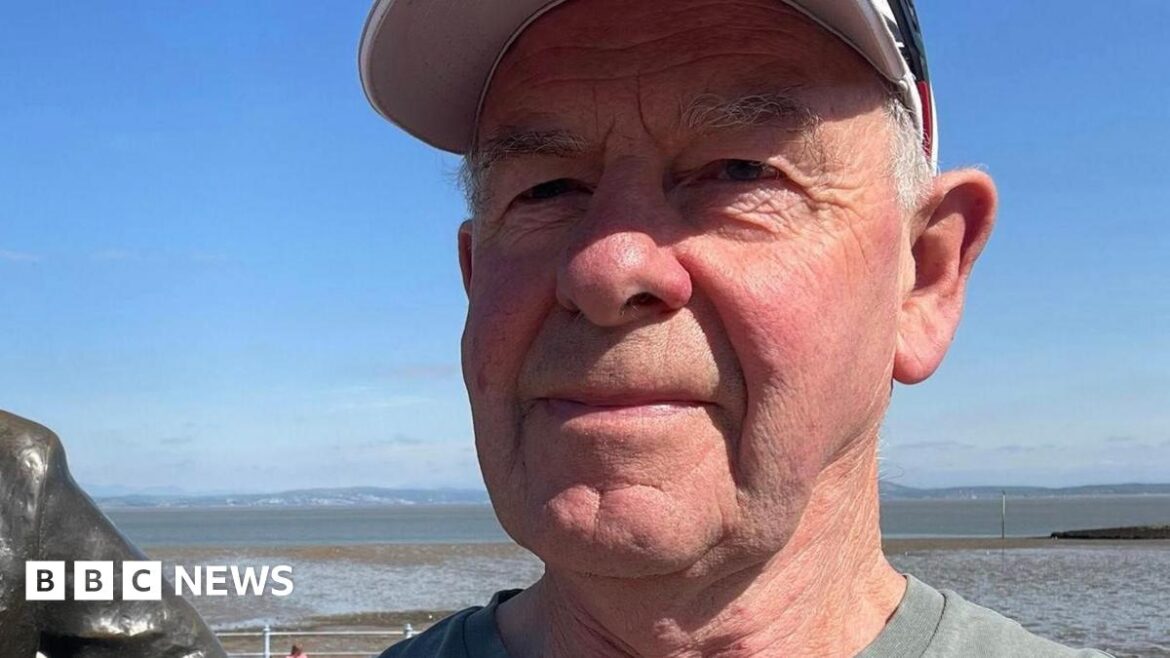 Suffolk eco-resident calls for artificial grass to be banned A selfie-style image of Jonathan Huggins. He is wearing a cap and a grey T-shirt. He is standing outside, seemingly on a coastline, while smiling and looking into the camera.