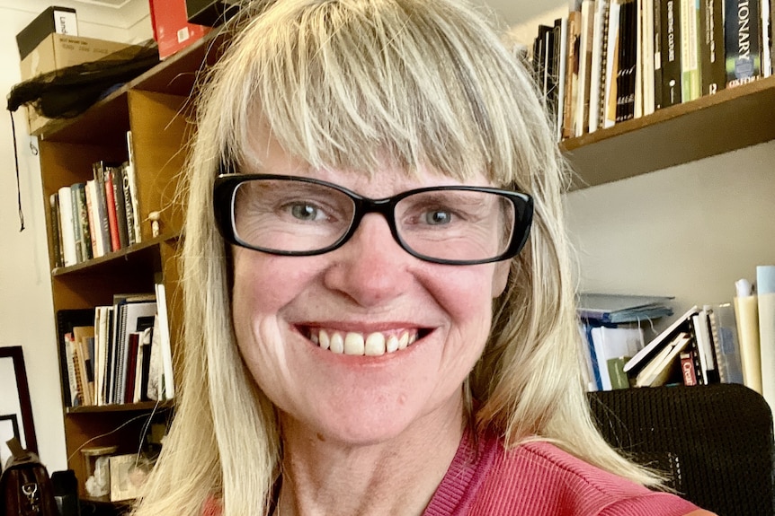 A woman smiles at the camera in her office