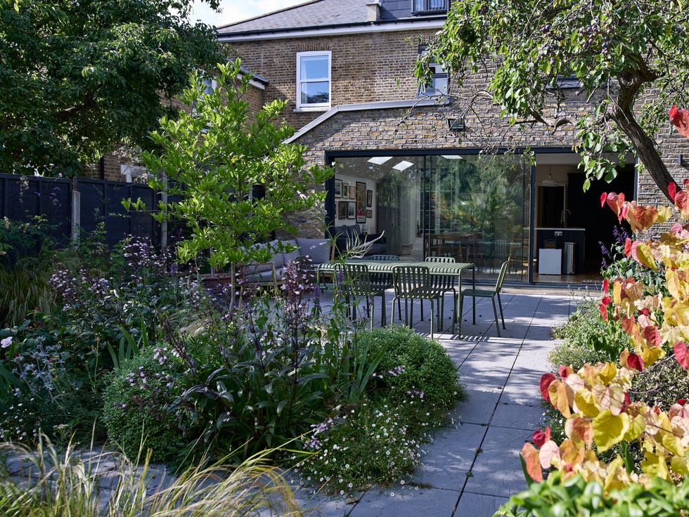 exterior of modern house with chairs and table arranged in back yard