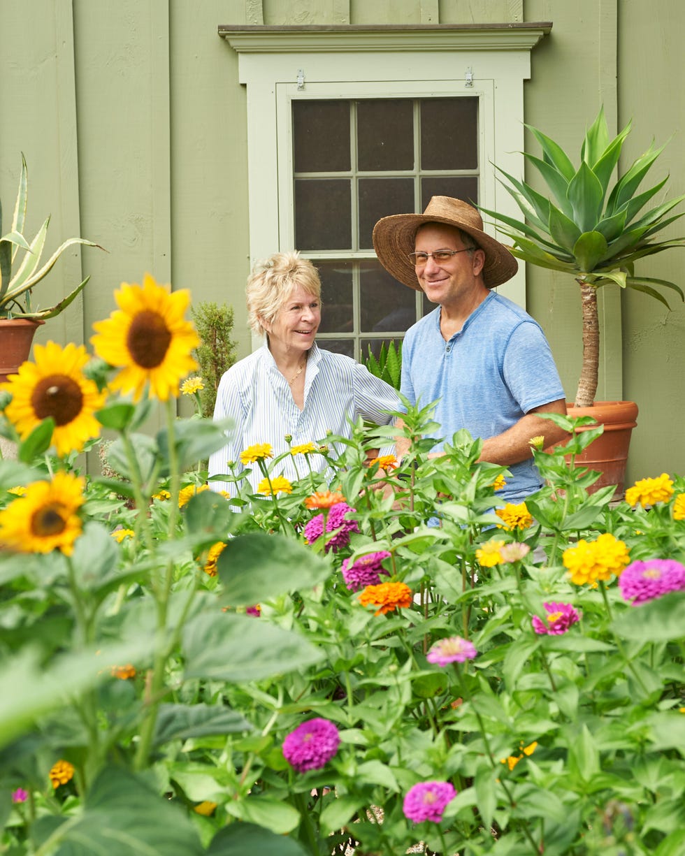Two people in a garden surrounded by colorful flowers