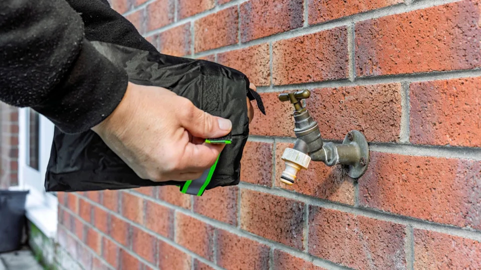 Person Installing Winter Frost Protection Insulated Tap Cover on Brass Garden Brick Wall Water Faucet