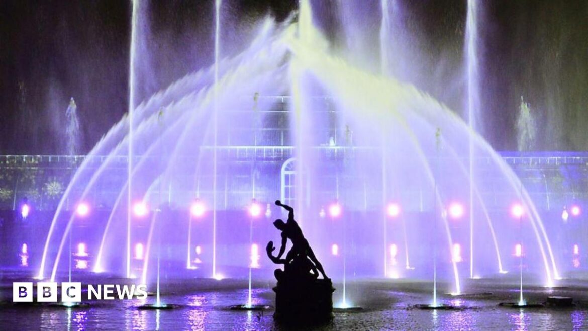 The Palm House at Kew Gardens is illuminated with a light show during a preview for the Christmas at Kew event on November 15, 2022 in London, with the Hercules statue in a silhouette in front of it.