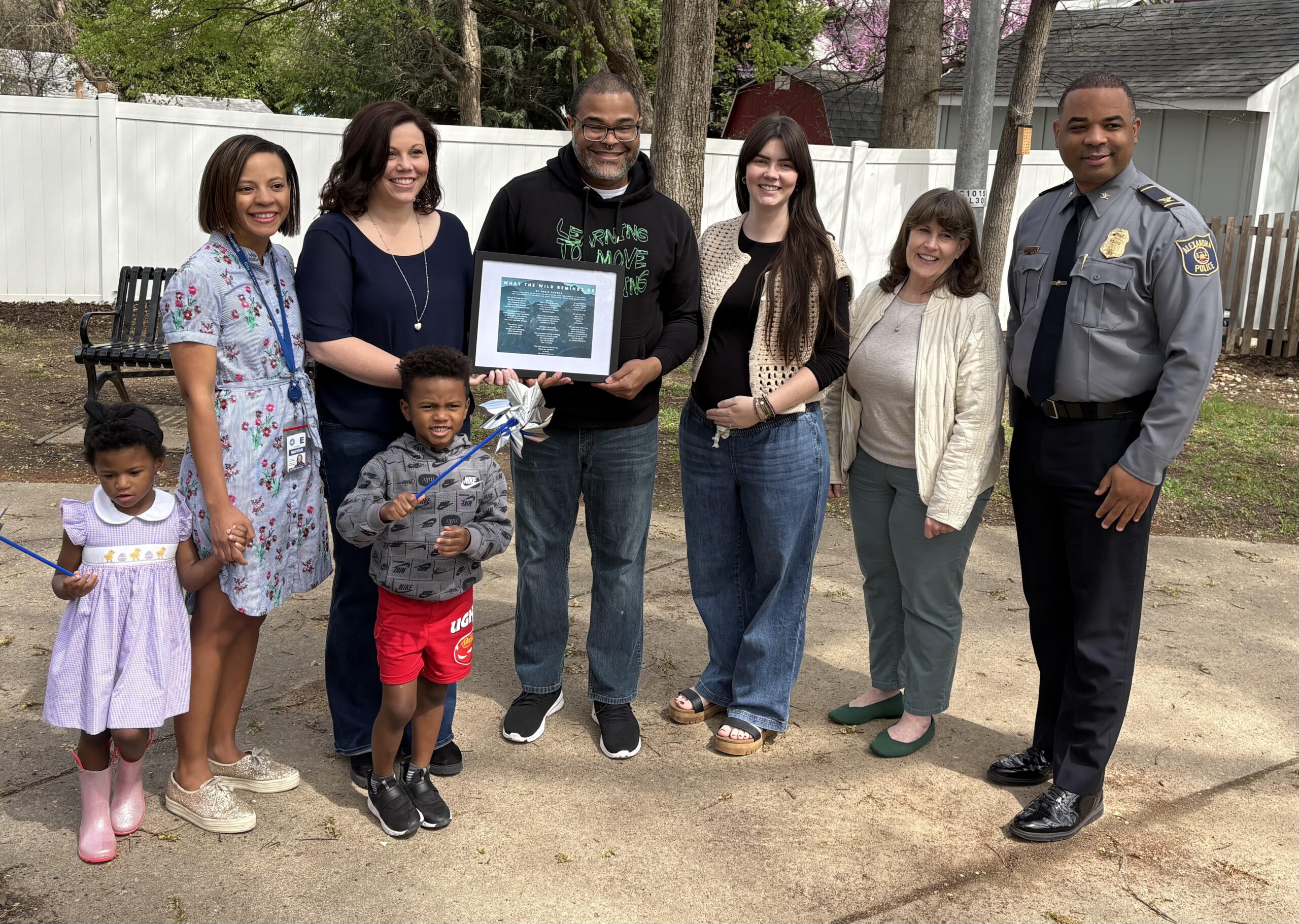 C. Thomas (center) presents his original poem to the Center for Alexandria's Children staff, with Mayor Alyia Gaskins and her children, Kate Garvey, and the Alexandria Police. 