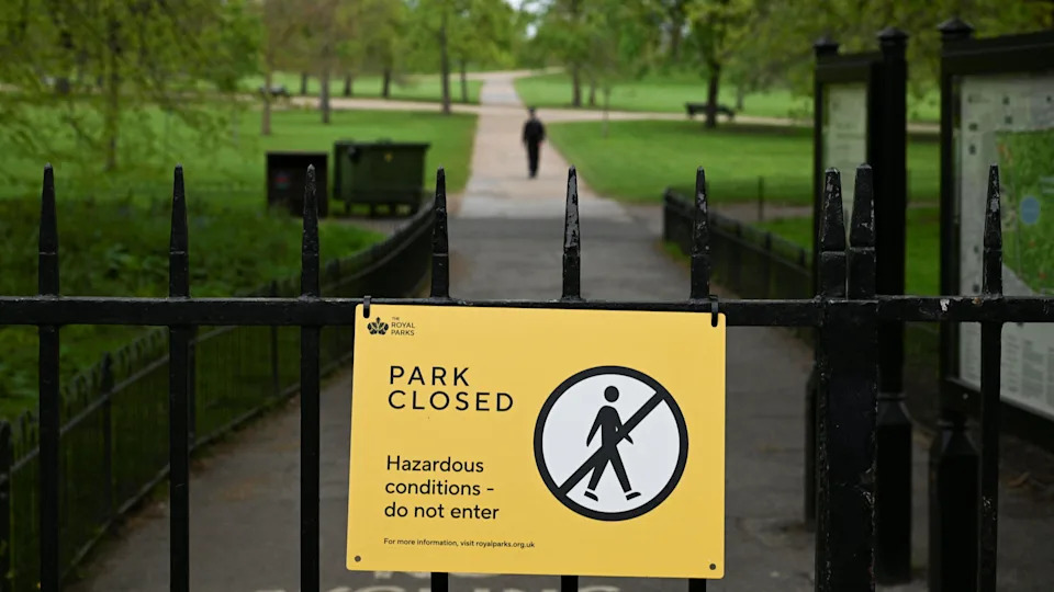 A yellow sign on a closed gate of the gardens, which says 'park closed'.