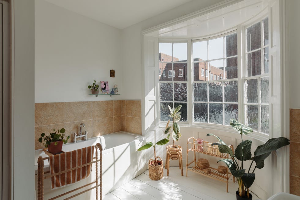 bright bathroom featuring a bathtub plants and large windows