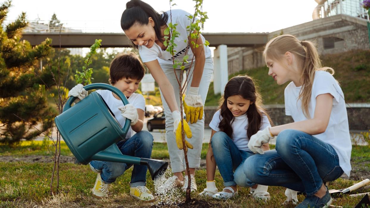 a mom plants a fruit tree with her kids