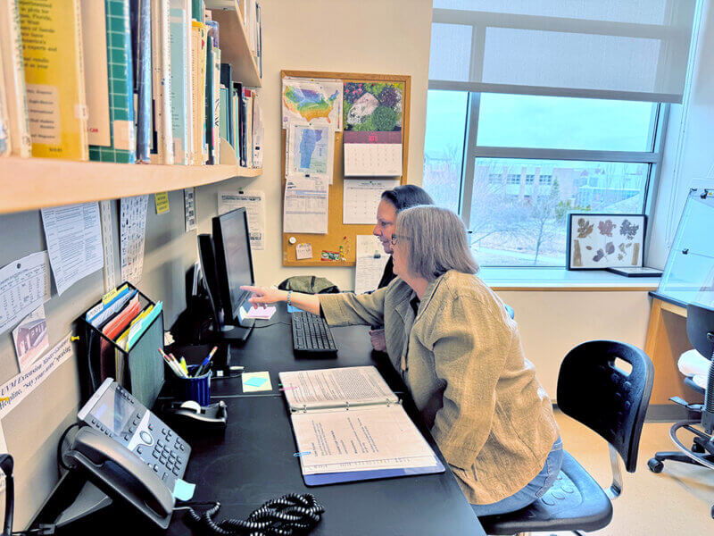 Photo by Debra Heleba.
University of Vermont Extension staffer Lisa Chouinard, left, and volunteer Gina Scafa of Burlington are ready by the helpline phone on April 2, the first day it opened for the 2026 gardening season.